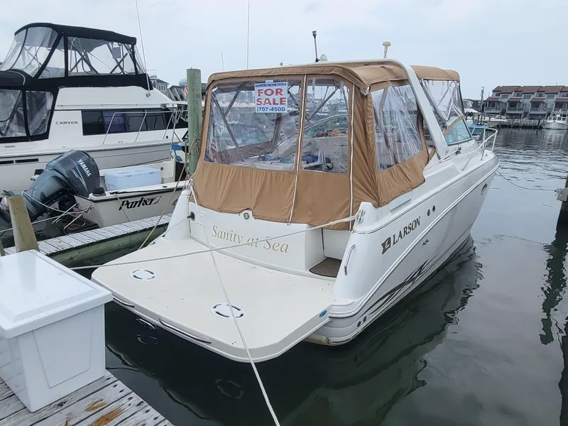 Slide: The Image of 2000 Larson Cabrio 290 boat docked, for sale sign displayed, beige canopy, marina setting. - 1