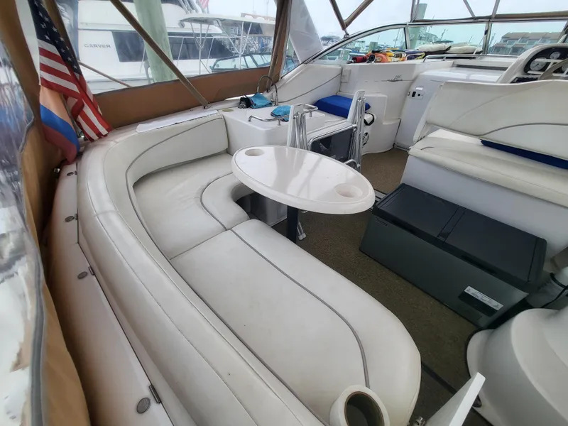 Slide: The Image of 2000 Larson Cabrio 290 boat interior with white seating, table, and American flag. - 11