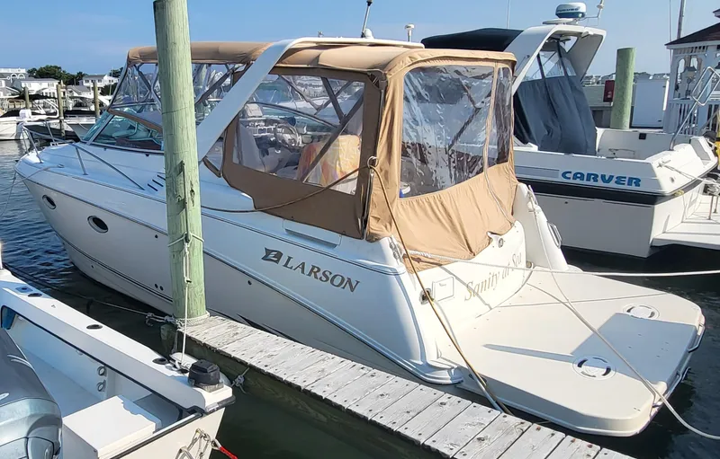 Slide: The Image of 2000 Larson Cabrio 290 boat docked with tan canopy and clear windows. - 13