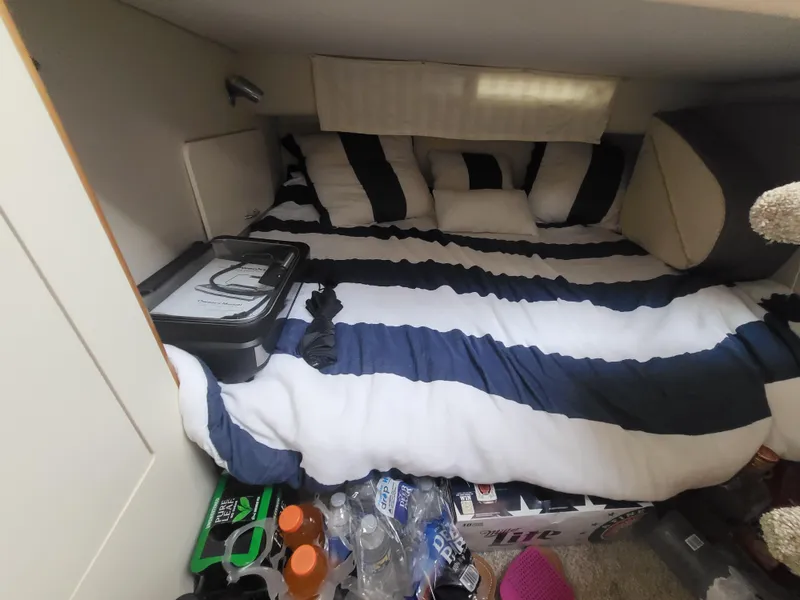 Slide: The Image of Cozy cabin interior of 2000 Larson Cabrio 290 with striped bedding and storage items. - 7