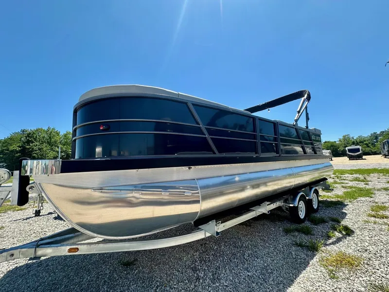 The Image of 2024 Massimo Marine P24-Limited Max pontoon boat on a trailer under clear blue sky. - 1