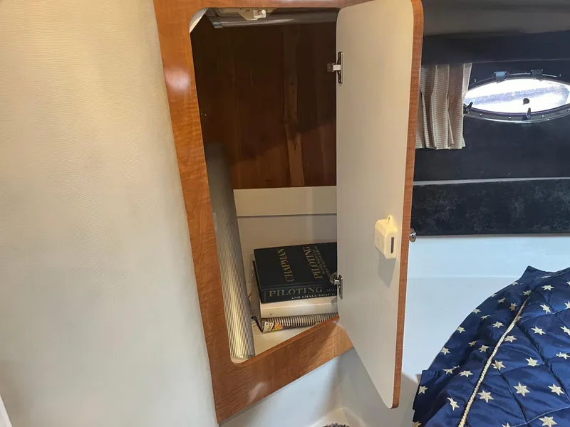 Slide: The Image of Open cabinet in 2003 Regal Commodore 3860 boat with books inside. - 31