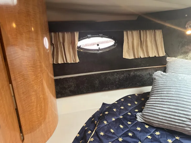 Slide: The Image of 2003 Regal Commodore 3860 cabin interior with bed, porthole, and wooden cabinetry. - 33