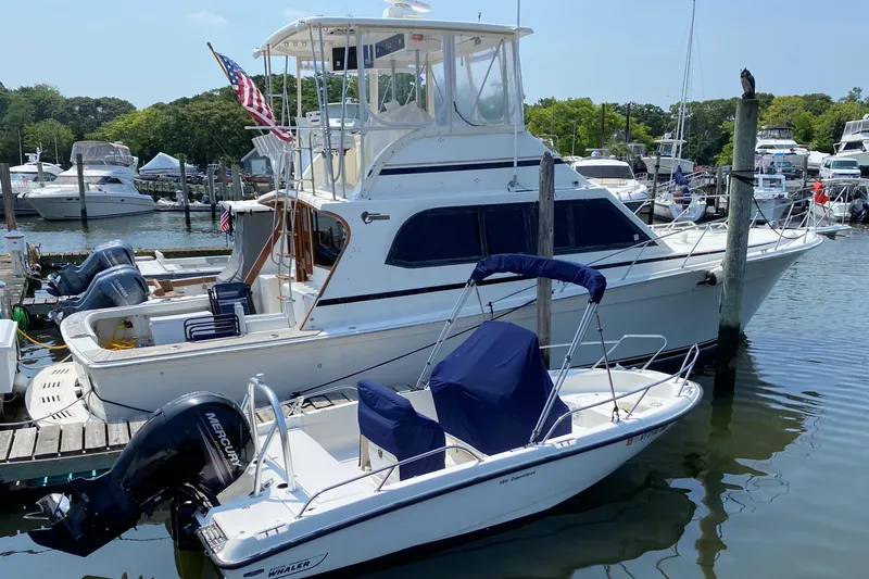 The Image of 1990 Egg Harbor 42 Golden Egg yacht docked beside a smaller motorboat in a marina. - 0