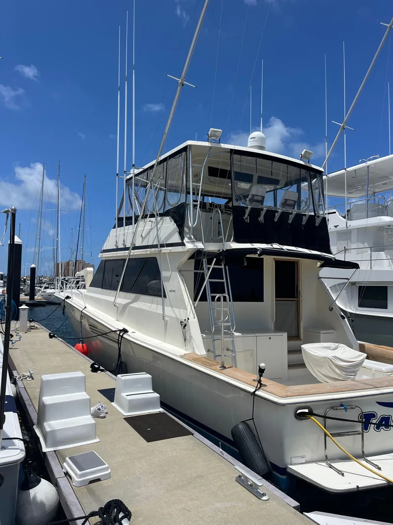 Slide: The Image of 1989 Viking 57 Convertible yacht docked at marina under clear blue sky. - 4