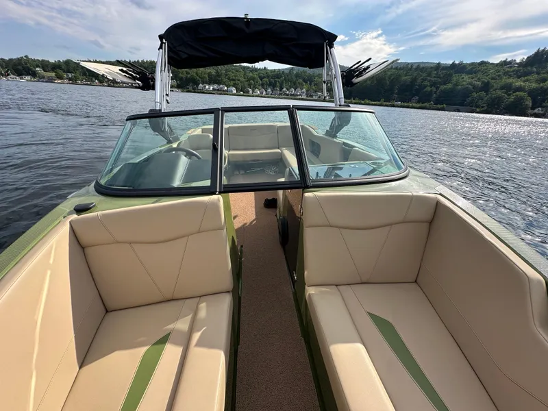 Slide: The Image of 2023 MasterCraft NXT 22 boat interior with beige seating on a lake. - 10