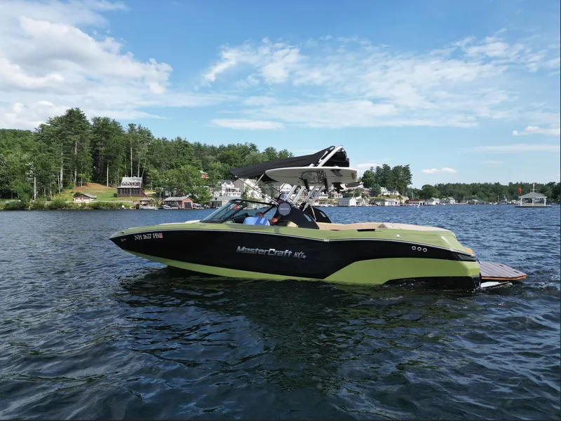 Slide: The Image of 2023 MasterCraft NXT 22 boat cruising on a lake with scenic background. - 26