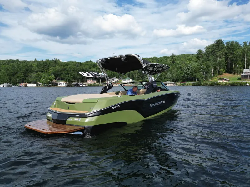Slide: The Image of 2023 MasterCraft NXT 22 boat on a lake with lush green shoreline. - 28