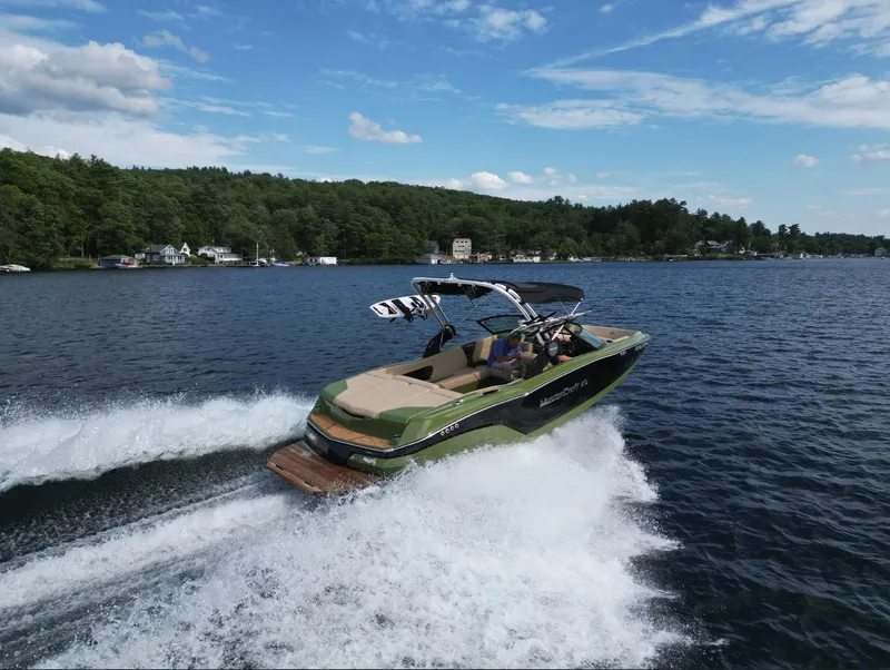 Slide: The Image of 2023 MasterCraft NXT 22 boat cruising on a lake with lush green shoreline. - 34