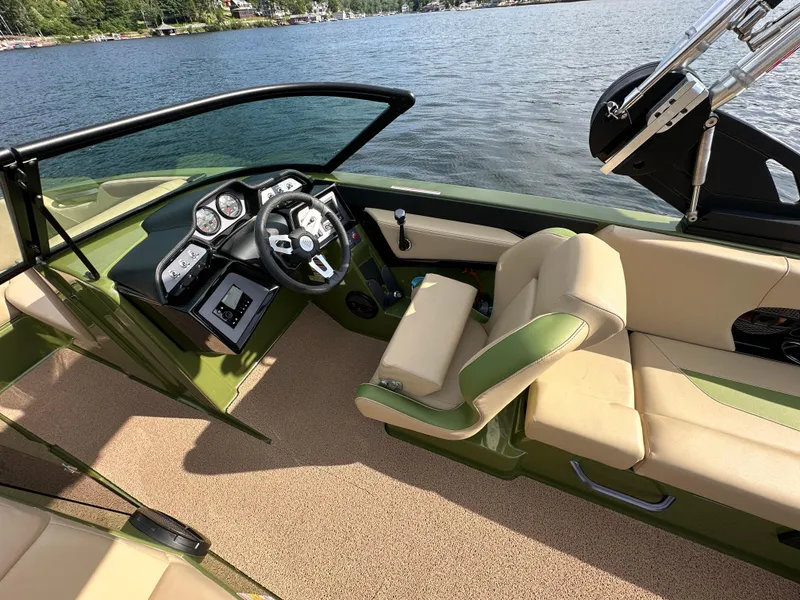 Slide: The Image of 2023 MasterCraft NXT 22 boat interior with beige and green seating, steering wheel, and dashboard. - 9