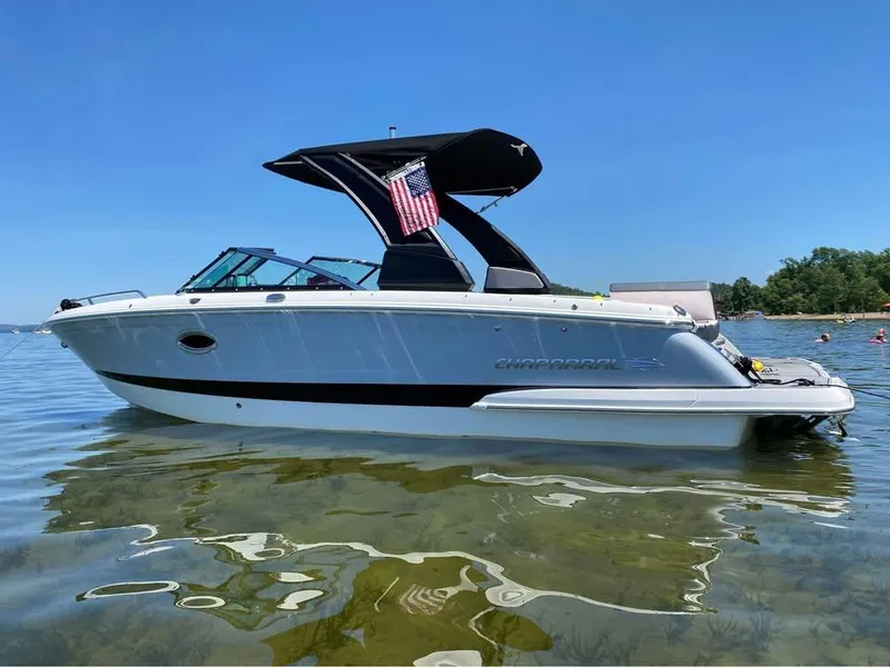 Slide: The Image of 2019 Chaparral 257 SSX boat on clear water, sunny day, American flag displayed. - 0