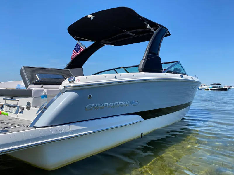 Slide: The Image of 2019 Chaparral 257 SSX boat with canopy on clear water under blue sky. - 2