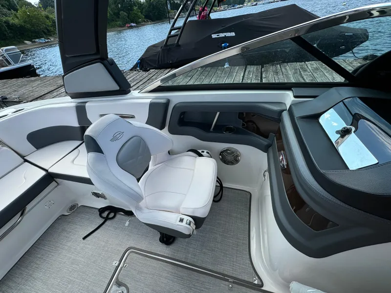 Slide: The Image of 2019 Chaparral 257 SSX boat interior with white seating and dashboard, docked by a lake. - 4