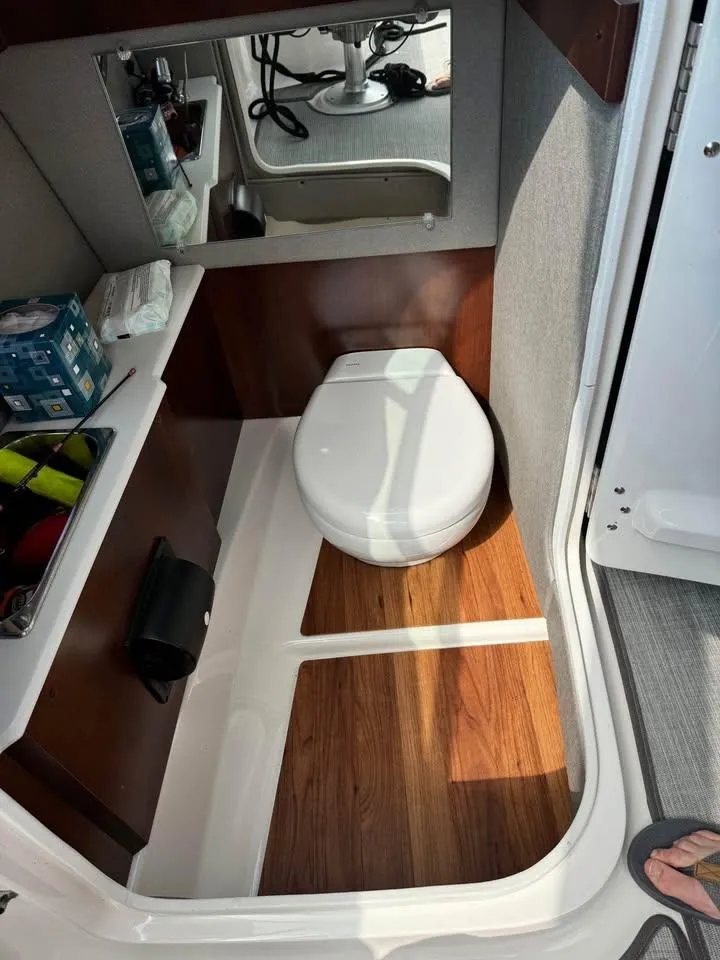 Slide: The Image of 2019 Chaparral 257 SSX boat bathroom with wooden flooring and compact toilet. - 5