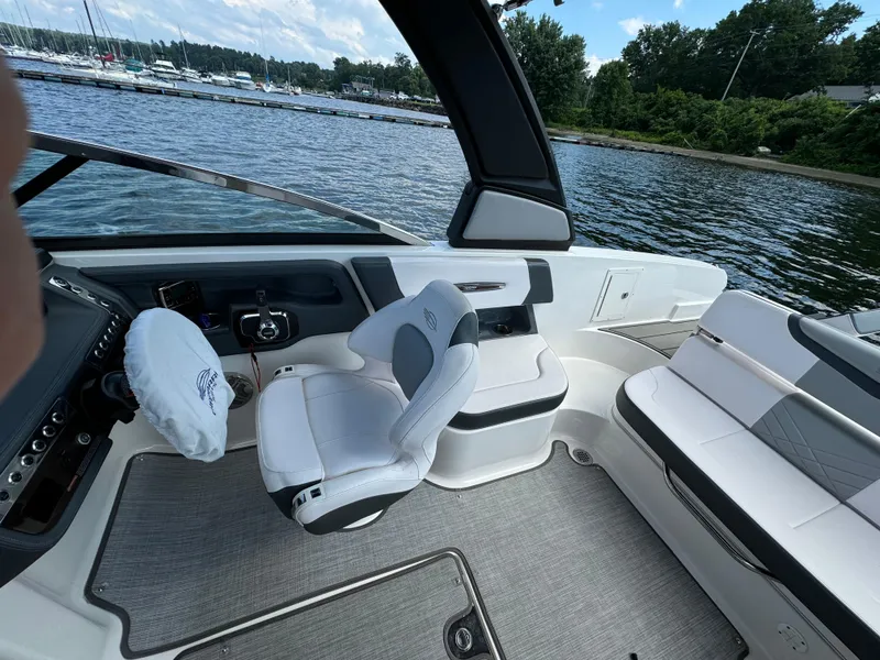 Slide: The Image of 2019 Chaparral 257 SSX boat interior with white seating, steering wheel, and lake view. - 6