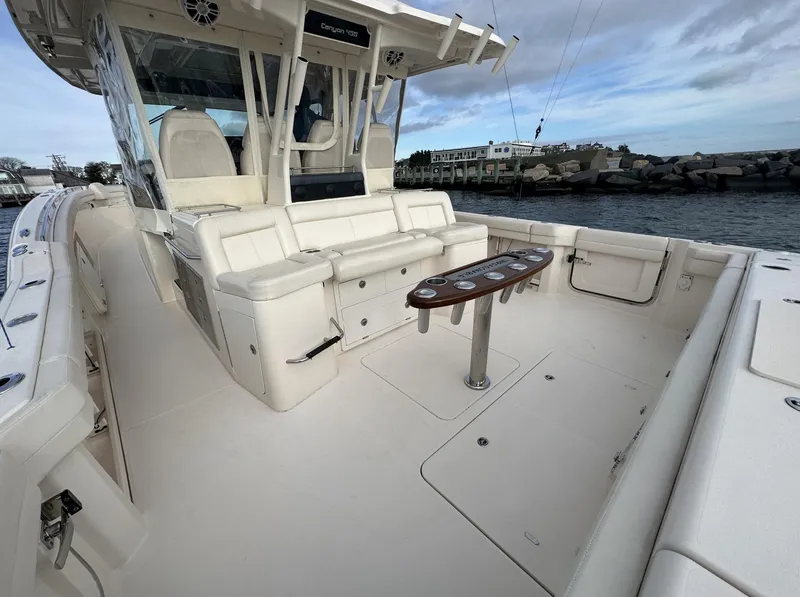Slide: The Image of 2019 Grady-White Canyon boat interior with seating and table, docked by the water. - 5