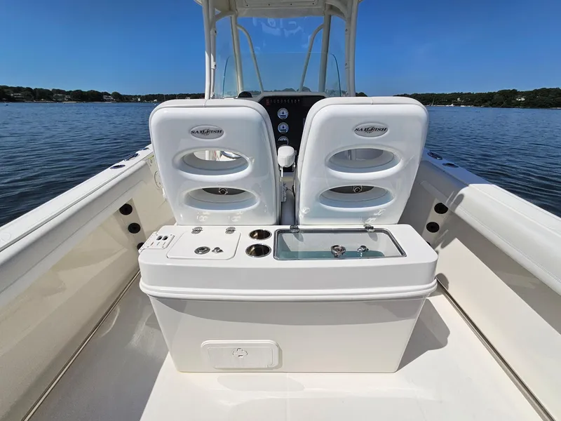 Slide: The Image of 2016 Sailfish 270 CC boat interior with dual seats and fishing equipment on a calm lake. - 12