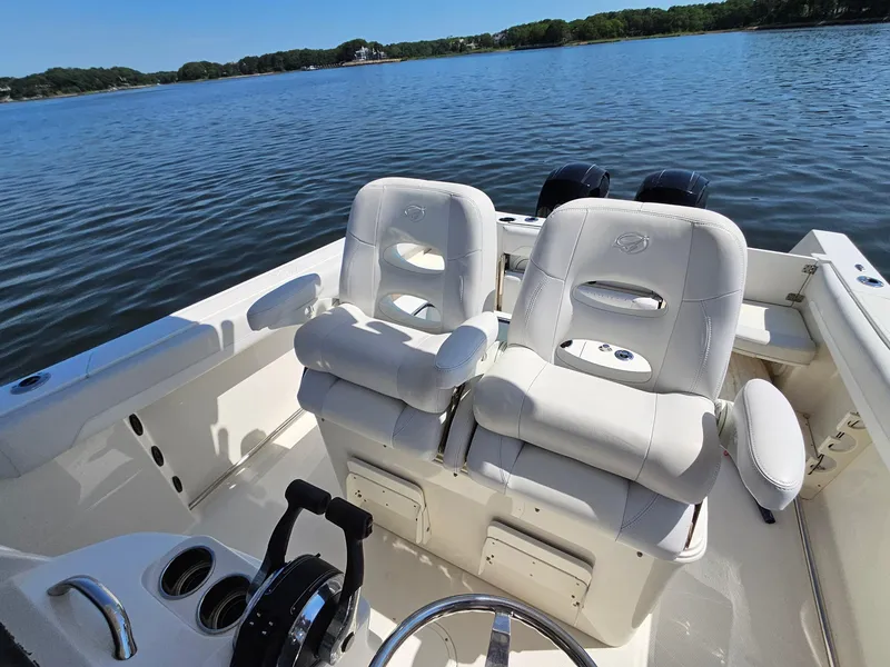 Slide: The Image of 2016 Sailfish 270 CC boat interior with dual white captain's chairs on a calm lake. - 14