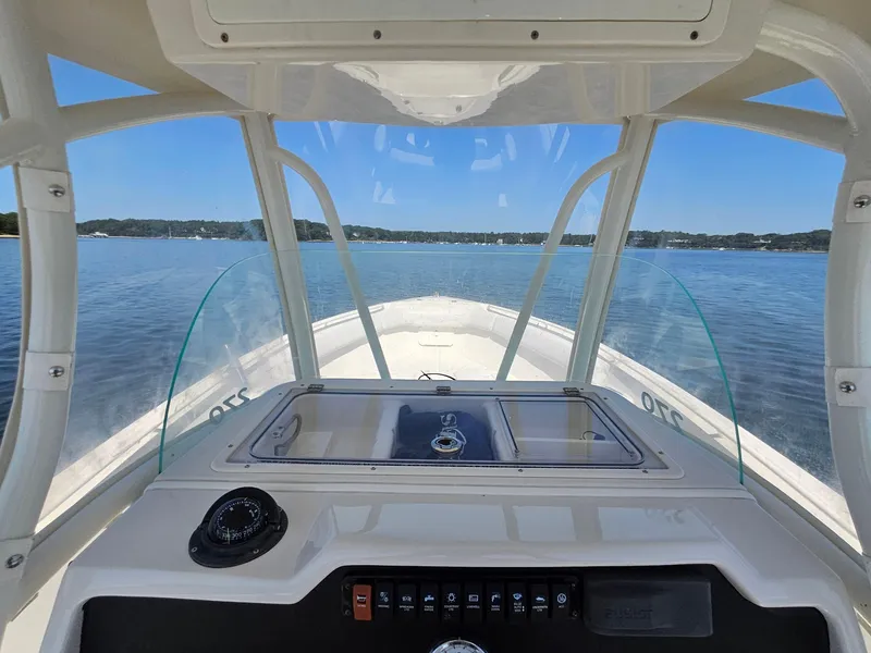 Slide: The Image of 2016 Sailfish 270 CC boat interior view with clear windshield and calm water backdrop. - 20