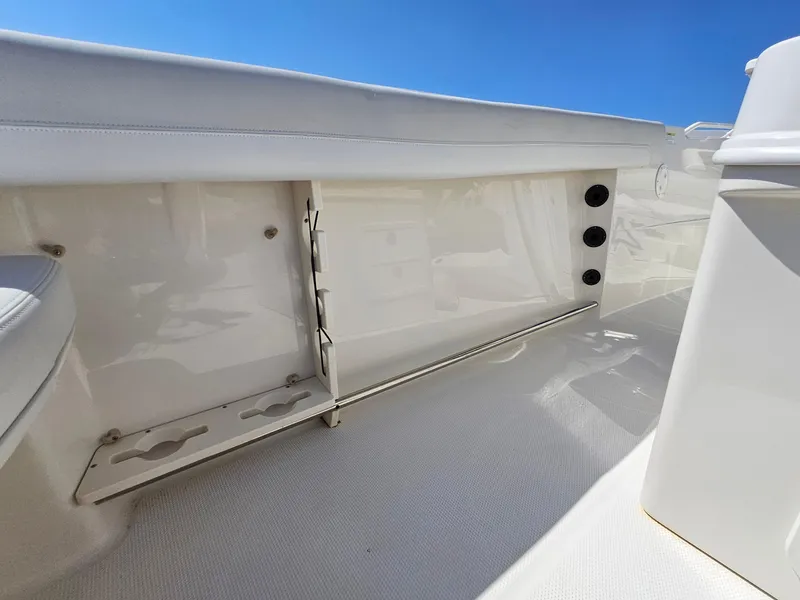 Slide: The Image of 2016 Sailfish 270 CC boat interior with rod holders and storage, under clear blue sky. - 27