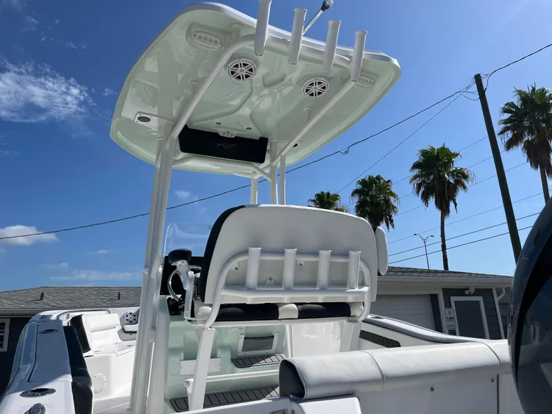 Slide: The Image of 2025 Tidewater 210 CC Adventure boat with T-top and rod holders, sunny day, palm trees. - 11