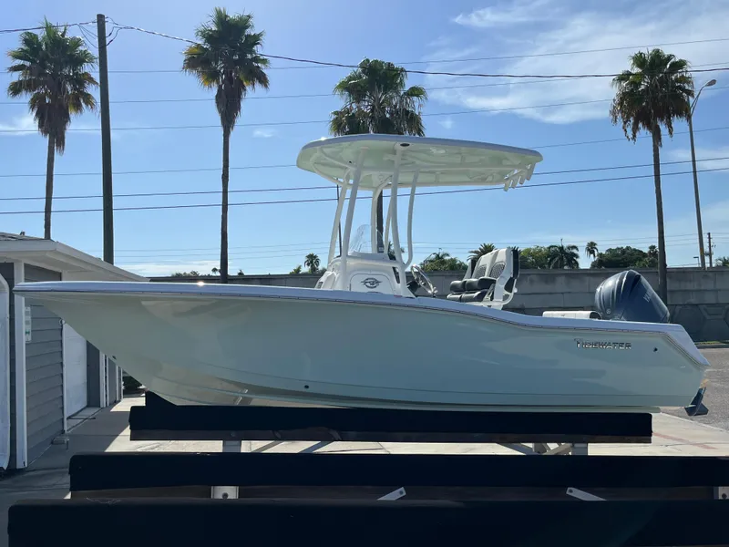 Slide: The Image of 2025 Tidewater 210 CC Adventure boat on display with palm trees in the background. - 2