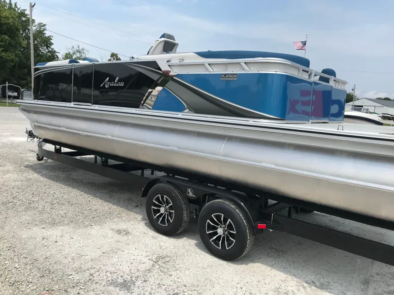 Slide: The Image of 2025 Avalon LSZ Quad Lounger pontoon boat displayed in a showroom. - 2