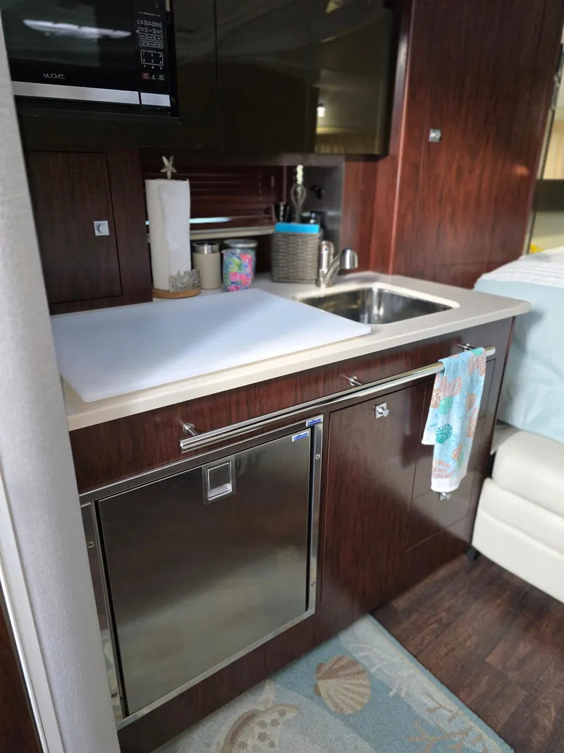 Slide: The Image of 2021 Monterey 335 Sport Yacht kitchen with sink, microwave, and wooden cabinetry. - 26