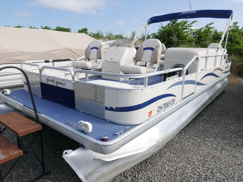 Slide: The Image of 2006 Sweetwater SW2222DF pontoon boat with blue and white seating, docked on gravel. - 1