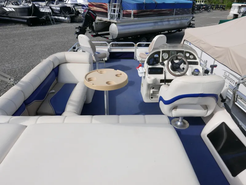Slide: The Image of 2006 Sweetwater SW2222DF pontoon boat interior with white and blue seating, steering console, and table. - 14