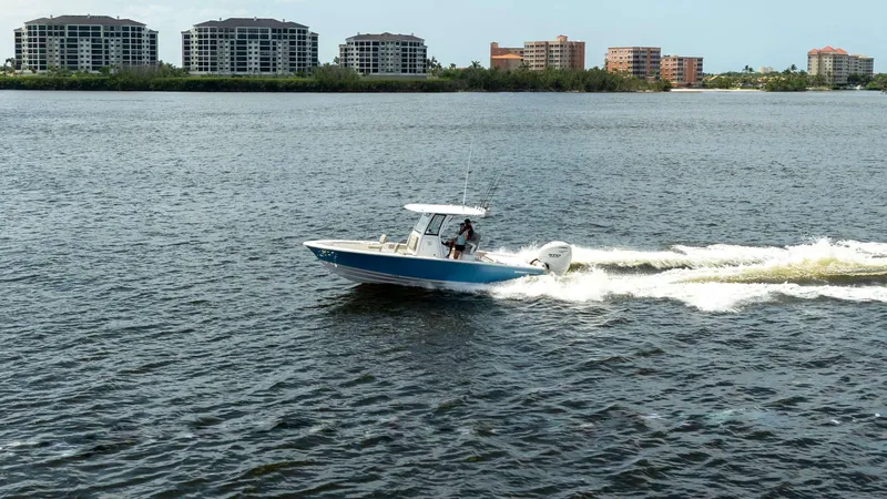 Slide: The Image of 2025 Sportsman 267 Masters boat cruising on a lake with cityscape in the background. - 2