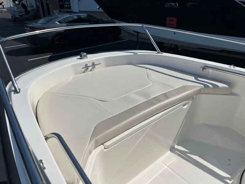 Slide: The Image of 2025 Boston Whaler 130 Super Sport boat interior with white seating and stainless steel railings. - 2