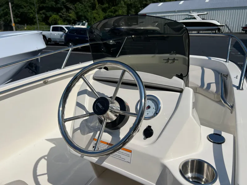 Slide: The Image of Boston Whaler 130 Super Sport 2025 boat steering console with windshield and stainless steel wheel. - 3