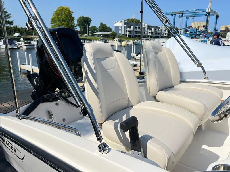 Slide: The Image of 2025 Boston Whaler 130 Super Sport boat with white leather seats docked at marina. - 5