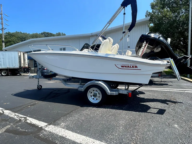 The Image of 2025 Boston Whaler 130 Super Sport boat on trailer in parking lot. - 0