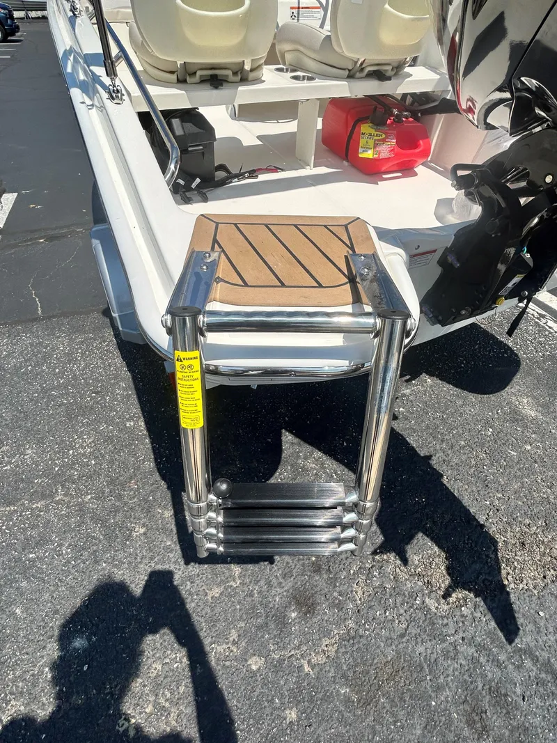 Slide: The Image of 2025 Boston Whaler 130 Super Sport boat with a foldable ladder and outboard motor. - 10