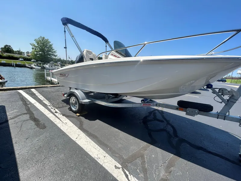 Slide: The Image of 2025 Boston Whaler 130 Super Sport boat on trailer at marina. - 2