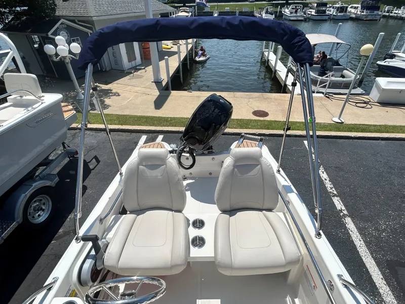Slide: The Image of 2025 Boston Whaler 130 Super Sport boat with dual seats and a bimini top at a marina. - 3