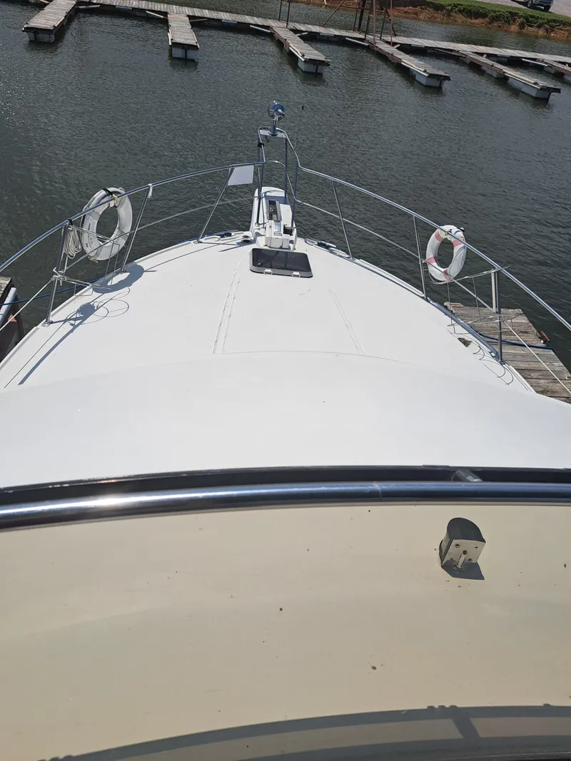 Slide: The Image of 1989 Carver 3807 yacht docked at a marina, view from the bow. - 3