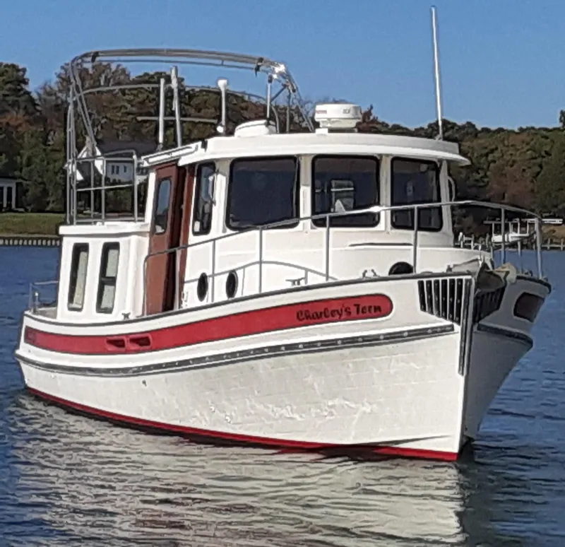 The Image of 1998 Nordic Tug 32 boat on calm water, featuring a white and red design. - 0