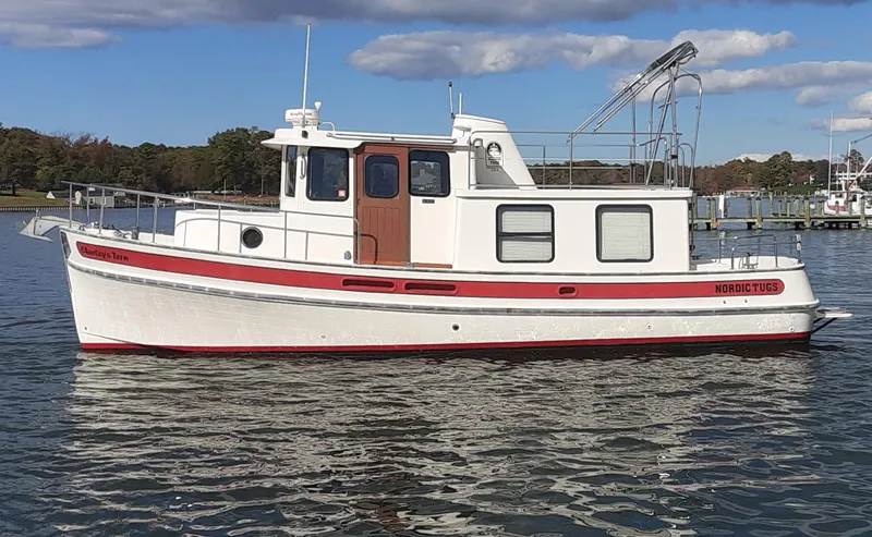 Slide: The Image of 1998 Nordic Tug 32 boat on calm water, featuring a classic design and red accents. - 1