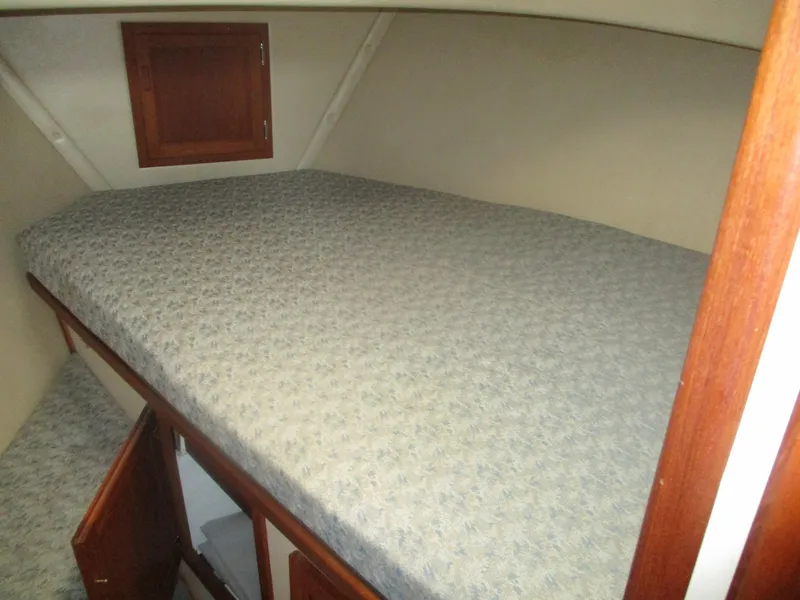 Slide: The Image of 1998 Nordic Tug 32 cabin interior with bed and wooden storage cabinets. - 17