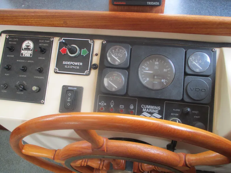 Slide: The Image of Control panel of a 1998 Nordic Tug 32 with gauges and wooden steering wheel. - 19