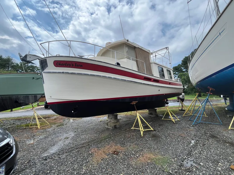 Slide: The Image of 1998 Nordic Tug 32 boat on stands, named "Charley's Tern," under cloudy sky. - 36