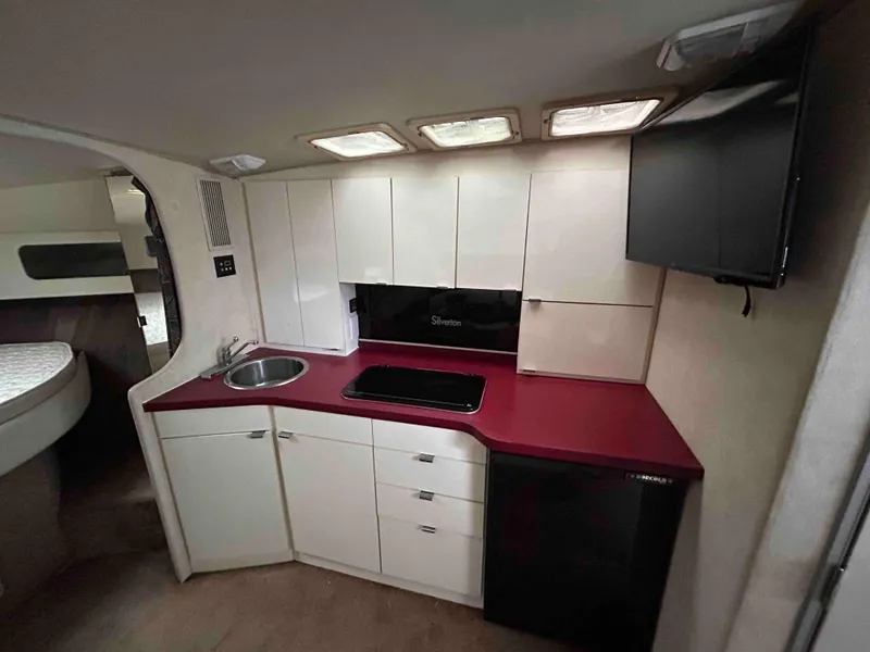 Slide: The Image of 1991 Silverton 34 Express Cruiser interior kitchen with red countertop and white cabinets. - 13