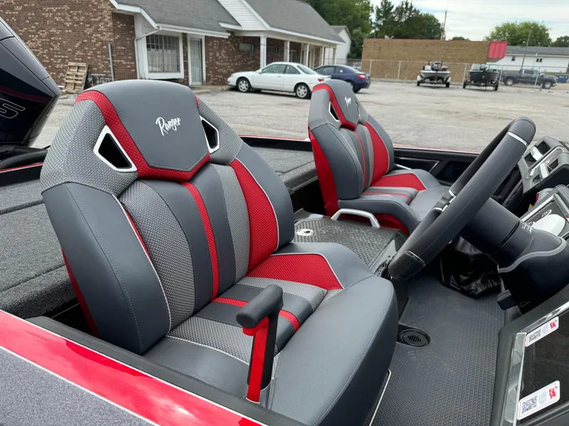 Slide: The Image of 2024 Ranger Z520R boat interior with red and gray seats, parked outdoors. - 10