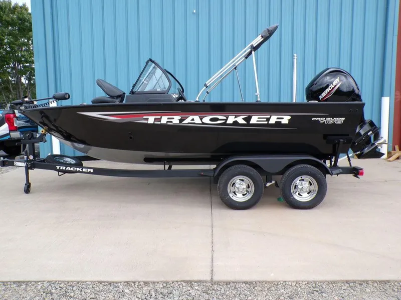 The Image of 2025 Tracker Pro Guide V-175 Combo boat on trailer, parked by blue building. - 1