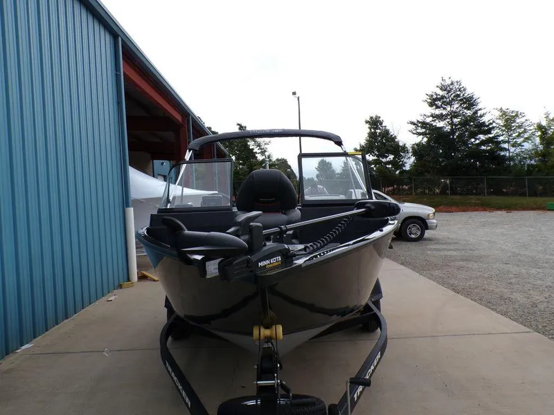 Slide: The Image of 2025 Tracker Pro Guide™ V-175 Combo boat on trailer, parked near blue building. - 3