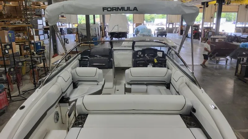 Slide: The Image of 2025 Formula 240 Bowrider boat interior in a warehouse, showcasing seating and helm. - 19