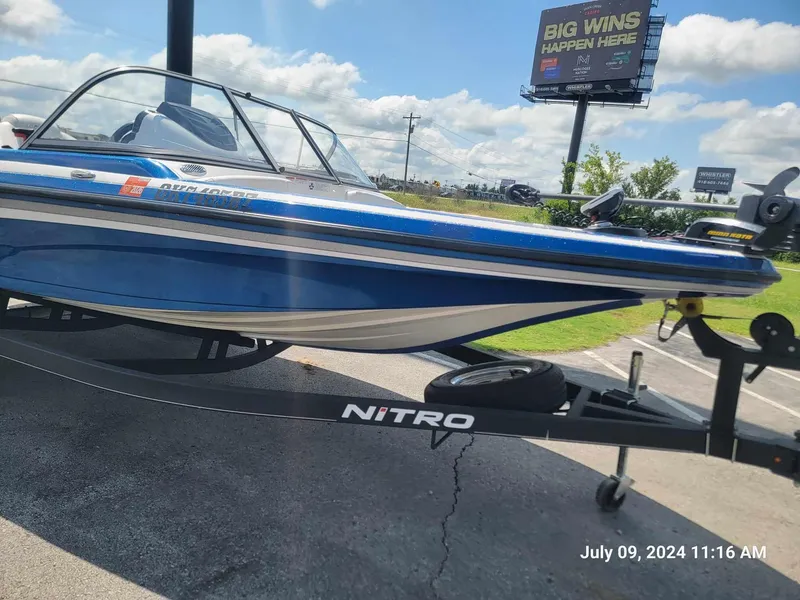 Slide: The Image of 2018 Nitro Z19 Sport blue boat on trailer, sunny day, billboard in background. - 10